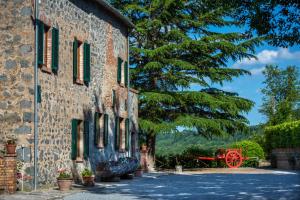 阿夸彭登泰Agriturismo Casale le Crete的砖砌建筑,设有绿色百叶窗和红色大炮