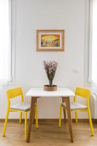 博洛尼亚Canonica Suites的一张桌子,上面有两把椅子和花瓶
