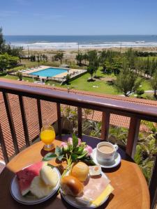 拉古纳Ravena Cassino Hotel的一张带早餐食品的桌子,享有海滩美景