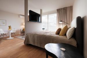 莱比锡SAXX Apartments Leipzig的一间卧室配有一张带电视和桌子的床。