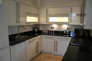 尚克林Shanklin Manor的厨房配有白色橱柜和黑色台面