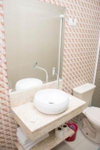 瓜鲁雅Hotel Morada do Mar的一间带水槽、卫生间和镜子的浴室