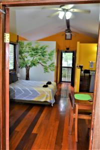 圣伊格纳西奥Sanpopo Tree Top Cottage - A Gold Standard Tourism Approved Vacation Home的卧室配有一张床铺,墙上挂着一棵树
