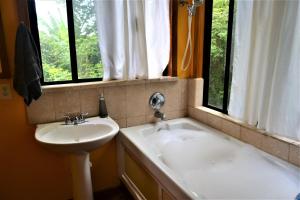 圣伊格纳西奥Sanpopo Tree Top Cottage - A Gold Standard Tourism Approved Vacation Home的浴室设有水槽和窗户旁的浴缸