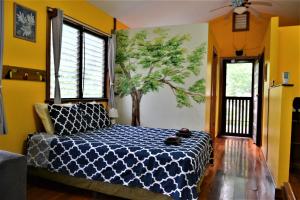 圣伊格纳西奥Sanpopo Tree Top Cottage - A Gold Standard Tourism Approved Vacation Home的卧室配有一张墙壁上涂有树的床铺。