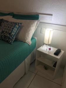 纳塔尔美利加多索旅馆的一张带床头柜的床,上面有灯