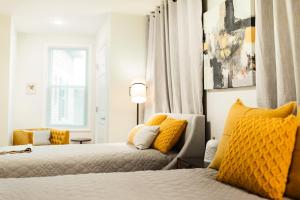 牛顿The Inn at Newton Highlands的一间卧室配有两张带黄色枕头的床