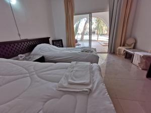 Al Azraq ash ShamālīAzraq Rest House的带大窗户的客房内的两张床