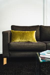 戴尔斯福特Daylesford Spa Accommodation的一张黑色沙发,配有黄色枕头和一张桌子
