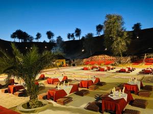 拉斯阿尔卡麦Bedouin Oasis Desert Camp- Ras Al Khaimah的庭院里设有红色的桌椅和棕榈树