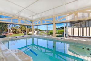 仙女港Dunes - Elegant Beach Villa with huge heated swim spa的一个带两把白色椅子和大玻璃墙的大型游泳池