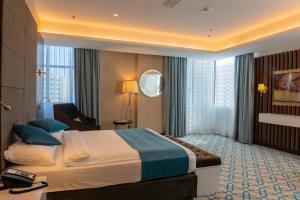 马斯喀特Royal Crown Hotel的酒店客房设有一张大床和一张书桌。