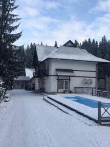 米库利钦Готель RIVER HILL的雪中带游泳池的房子