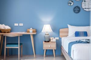 芭堤雅市中心DeeProm Pattaya Hotel的一间卧室设有蓝色的墙壁、一张床和一张书桌