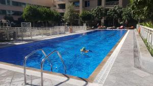 迪拜Durrani Homes - Designer 2BR Apt with stunning Burj khalifa and Fountain View的在大型蓝色游泳池游泳的人