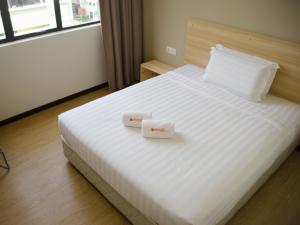 双溪毛糯1 Orange Hotel Sungai Buloh的卧室配有白色的床和2盒