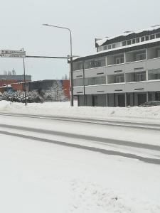 耶姆赛Koskentien yksiö的雪中建筑物前面一条空的街道