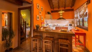 FontibreCASUCAS LA GUARIZA ( Casa Marta)的厨房设有橙色墙壁和带凳子的台面