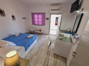 费拉安托公寓式酒店的一间卧室配有一张床、一张桌子和一个紫色的窗户