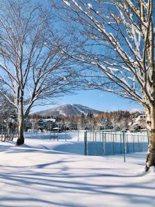 八幡平市安比美丽人生宾馆的一座有雪覆盖的公园,里面种有树木,并有栅栏