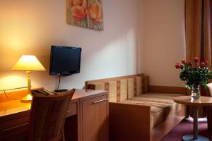 柏林柏林猎户座酒店的客房设有一张沙发和一张带电视的书桌。