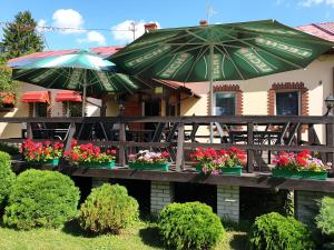 KosewoGościniec LECH的餐厅前方的庭院里摆放着鲜花和遮阳伞