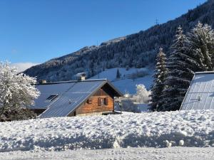 卡普伦AlpinResort Kaprun 2的雪地中的小木屋,设有太阳能电池板