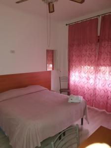 钱皮诺艾尔伯格安娜酒店的一间卧室配有一张床和粉红色窗帘