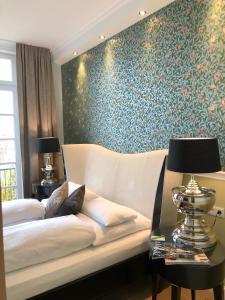 塞斯豪普特斯塔恩堡西酒店的一间卧室配有床和壁纸覆盖的墙壁