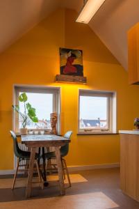韦斯特卡佩勒海滨一室公寓的一间拥有黄色墙壁、桌子和2个窗户的用餐室
