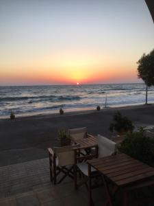 阿齐亚·佩拉加·基西拉Anesis Hotel的海滩上的日落,配有桌椅