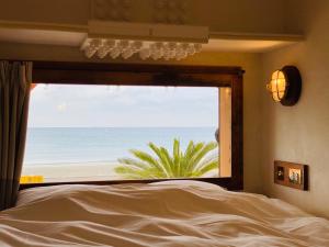 镰仓市GOOD MORNING ZAIMOKUZA的一间卧室设有窗户,享有海滩美景
