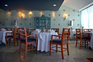 韦拉克鲁斯里沃利斯尔德酒店的一间设有白色桌椅的用餐室和一间设有绿色墙壁的客房