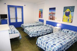 莱斯卡拉Pensió Solivent的配有蓝色和白色床单的客房内的三张床