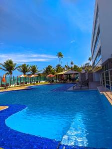 康德Tabatinga Flat - Beira Mar的一座种植了棕榈树和遮阳伞的大型蓝色游泳池