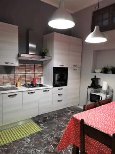 米兰Bnbook-Villa Molinari的厨房配有白色橱柜和一张带红色桌布的桌子