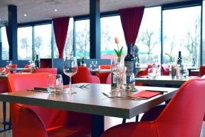 鹿特丹鹿特丹南巴斯蒂欧酒店的餐厅设有红色椅子和带酒杯的木桌