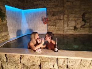 奥尼萨诺B&B Casa di Anita的男人和女人坐在热水浴缸里,喝一瓶葡萄酒