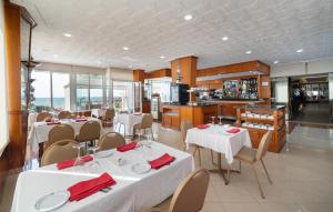 林孔-德拉维多利亚林孔索尔酒店的一间带白色桌椅的餐厅和一间厨房