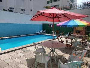 若昂佩索阿Regiane Beach Pousada Hostel的游泳池旁带桌子和遮阳伞的天井
