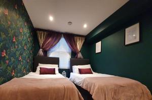 巴斯Enchanted Hideaway, Bath的配有两张床的客房,设有绿色的墙壁和窗户