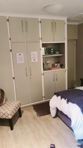 哈里史密斯THE SPARE BEDROOM Unit 1的卧室配有白色橱柜、一张床和一把椅子