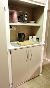 哈里史密斯THE SPARE BEDROOM Unit 1的厨房配有带台面的白色橱柜