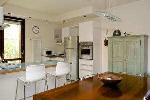 加尔达Villa con ampio giardino esterno e piscina condominiale的厨房配有木桌和白色椅子