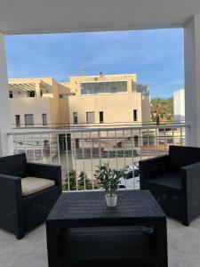 卡拉隆加Apartamentos Torres Cardona (Playa)的阳台配有两把椅子和一张桌子,公寓大楼