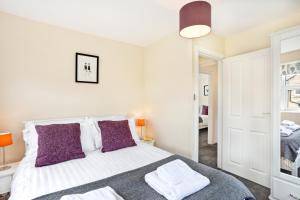 哈罗盖特The Harrogate Penthouse的卧室配有一张带紫色枕头的大型白色床。
