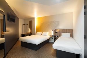 马恩河畔的尚格尼B&B HOTEL Champigny-sur-Marne的一间酒店客房,设有两张床和电视