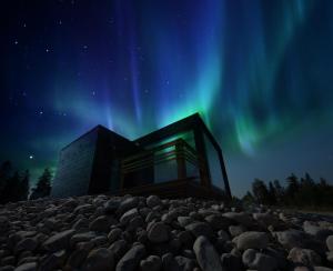 HyrynsalmiUkkohalla Sky Cabin Glass Suite的天空北灯下的房屋