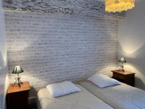 布里阿尔Gites de la Thiau的卧室设有2张床,设有砖墙