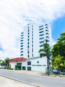 累西腓Hotel Nacional Inn Recife Aeroporto的一座白色的建筑,前面有棕榈树